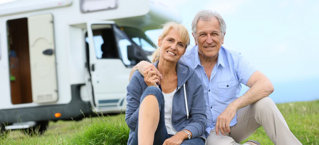 Senior couple sitting in front of camper van
